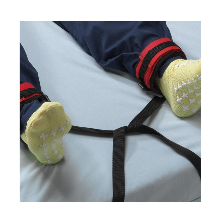 a persons feet secured to a bed with the posey ankle restraint 